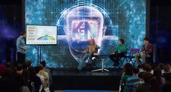 Movie still from “Dumb and Dumber To” (2014), directed by Peter Farrelly – Two people sitting on chairs in front of a screen; Wide shot, Over the shoulder angle