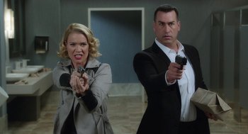 Movie still from “Dumb and Dumber To” (2014), directed by Peter Farrelly – A man and a woman holding guns in a room; Medium shot, Low angle