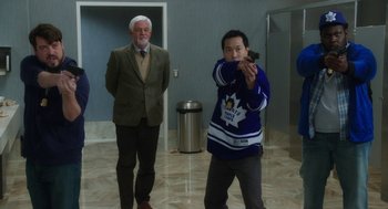 Movie still from “Dumb and Dumber To” (2014), directed by Peter Farrelly – A man in a hockey jersey taking a picture with a cell phone; Medium shot, Over the shoulder angle