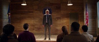 Movie still from “Dying of the Light” (2014), directed by Paul Schrader – A man standing on a stage in front of a crowd of onlookers; Wide shot, Low angle