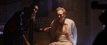 Movie still from “Dying of the Light” (2014), directed by Paul Schrader – A man is sitting in a chair with another man pointing at him; Medium shot, Over the shoulder angle