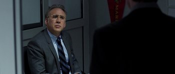 Movie still from “Dying of the Light” (2014), directed by Paul Schrader – A man in a suit and tie sitting in front of another man; Close Up shot, Over the shoulder angle