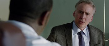 Movie still from “Dying of the Light” (2014), directed by Paul Schrader – A man wearing a suit and tie talking to another man; Close Up shot, Over the shoulder angle
