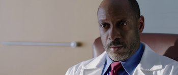 Movie still from “Dying of the Light” (2014), directed by Paul Schrader – A person wearing a lab coat and tie; Close Up shot, Low angle