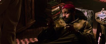 Movie still from “Dying of the Light” (2014), directed by Paul Schrader – A man with a beard is smoking a pipe; Medium shot, High angle