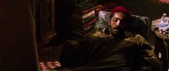 Movie still from “Dying of the Light” (2014), directed by Paul Schrader – A man sleeping on a chair with a bunch of books in the background; Medium shot, High angle