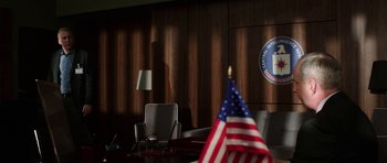 Movie still from “Dying of the Light” (2014), directed by Paul Schrader – An american flag in a conference room setting; Wide shot, Low angle
