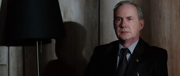 Movie still from “Dying of the Light” (2014), directed by Paul Schrader – An older man wearing a suit and tie in front of a mirror; Close Up shot, Over the shoulder angle