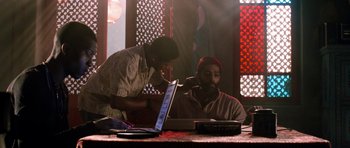 Movie still from “Dying of the Light” (2014), directed by Paul Schrader – Two men sitting in front of a laptop computer; Medium shot, Over the shoulder angle