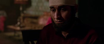 Movie still from “Dying of the Light” (2014), directed by Paul Schrader – A person with a beard wearing a hat; Close Up shot, Over the shoulder angle