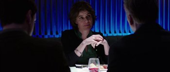 Movie still from “Dying of the Light” (2014), directed by Paul Schrader – A woman sitting at a table in front of a glass of wine; Medium shot, Over the shoulder angle