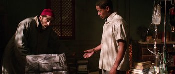 Movie still from “Dying of the Light” (2014), directed by Paul Schrader – A man standing next to a stack of books; Medium shot, High angle
