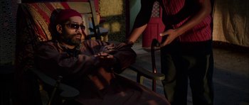 Movie still from “Dying of the Light” (2014), directed by Paul Schrader – A man sitting in a chair next to another man holding a cane; Medium shot, Over the shoulder angle