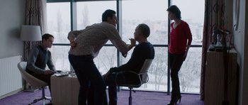 Movie still from “Dying of the Light” (2014), directed by Paul Schrader – Two men and a woman in an office setting; Medium shot, Over the shoulder angle