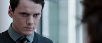 Movie still from “Dying of the Light” (2014), directed by Paul Schrader – A young man looking at the camera while wearing a sweater; Close Up shot, Over the shoulder angle