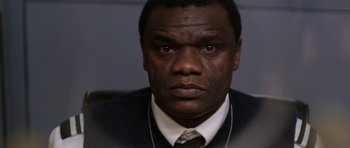 Movie still from “Dying of the Light” (2014), directed by Paul Schrader – A person wearing a suit and tie; Close Up shot, Over the shoulder angle