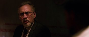 Movie still from “Dying of the Light” (2014), directed by Paul Schrader – An older man in a suit and glasses; Close Up shot, Over the shoulder angle