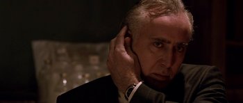 Movie still from “Dying of the Light” (2014), directed by Paul Schrader – An older man in a suit and tie holding his hand to his ear; Close Up shot, Over the shoulder angle