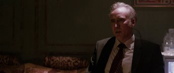 Movie still from “Dying of the Light” (2014), directed by Paul Schrader – An older man wearing a suit and tie in a room; Close Up shot, Over the shoulder angle