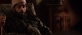 Movie still from “Dying of the Light” (2014), directed by Paul Schrader – A man sitting in a chair wearing a crown; Close Up shot, High angle