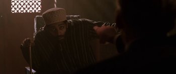 Movie still from “Dying of the Light” (2014), directed by Paul Schrader – A man with a hat is looking at a mirror; Medium shot, Over the shoulder angle