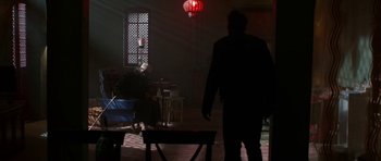 Movie still from “Dying of the Light” (2014), directed by Paul Schrader – A person standing in a room with a red lantern; Wide shot, Over the shoulder angle