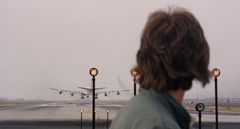 Movie still from “Easy Rider” (1969), directed by Dennis Hopper – A man standing in front of an airport runway; Wide shot, Over the shoulder angle