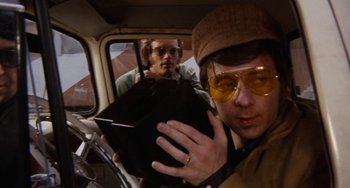 Movie still from “Easy Rider” (1969), directed by Dennis Hopper – A man in a hat and sunglasses in the back of a car; Close Up shot, Low angle