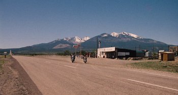 Movie still from “Easy Rider” (1969), directed by Dennis Hopper – Two motorcycles are parked on the side of the road; Extreme Wide shot, Low angle