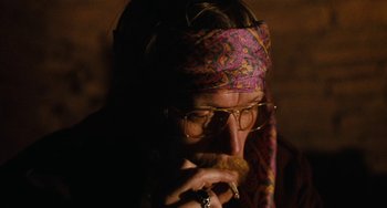 Movie still from “Easy Rider” (1969), directed by Dennis Hopper – A man with a beard and glasses wearing a head scarf; Close Up shot, Over the shoulder angle