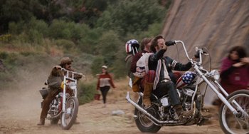 Movie still from “Easy Rider” (1969), directed by Dennis Hopper – A group of people riding motorcycles on a dirt road; Wide shot, Low angle