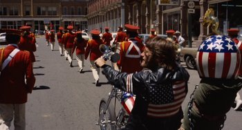 Movie still from “Easy Rider” (1969), directed by Dennis Hopper – A group of people marching down a street with bikes; Wide shot, Low angle
