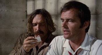 Movie still from “Easy Rider” (1969), directed by Dennis Hopper – Two men sitting next to each other and one of them is holding a cell phone; Close Up shot, Low angle