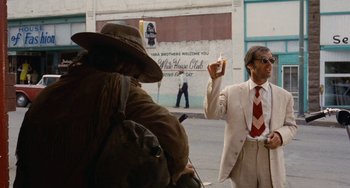 Movie still from “Easy Rider” (1969), directed by Dennis Hopper – A man in a white suit and red tie holding a sandwich; Wide shot, Low angle