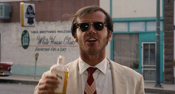 Movie still from “Easy Rider” (1969), directed by Dennis Hopper – A man in a suit and tie holding a bottle of beer; Close Up shot, Low angle
