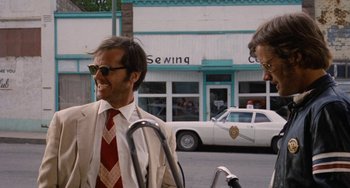 Movie still from “Easy Rider” (1969), directed by Dennis Hopper – A man in a suit and tie next to another man in sunglasses; Medium shot, Low angle