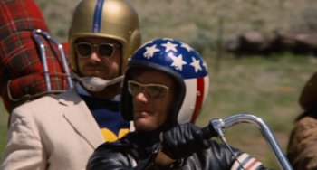 Movie still from “Easy Rider” (1969), directed by Dennis Hopper – Two men on a motorcycle wearing helmets and goggles; Close Up shot, Low angle