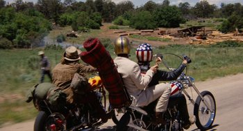 Movie still from “Easy Rider” (1969), directed by Dennis Hopper – A group of people riding motorcycles on a dirt road; Wide shot, Low angle