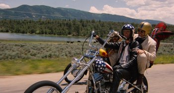 Movie still from “Easy Rider” (1969), directed by Dennis Hopper – Two people on a motor bike on the side of the road; Wide shot, Low angle