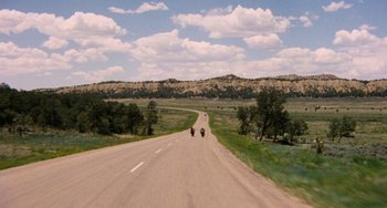 Movie still from “Easy Rider” (1969), directed by Dennis Hopper – Two people riding motorcycles down the middle of a road; Extreme Wide shot, High angle