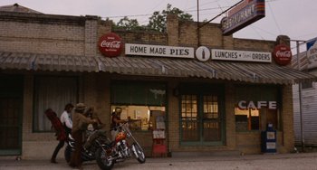Movie still from “Easy Rider” (1969), directed by Dennis Hopper – Two men sitting on a motorcycle in front of a store; Wide shot, Low angle