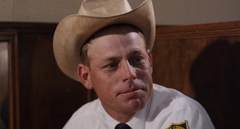 Movie still from “Easy Rider” (1969), directed by Dennis Hopper – A police officer wearing a cowboy hat and tie; Close Up shot, Low angle