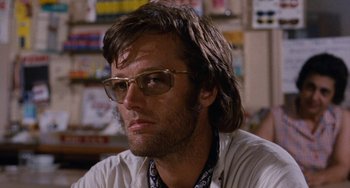 Movie still from “Easy Rider” (1969), directed by Dennis Hopper – A person wearing glasses and a white shirt; Close Up shot, Low angle