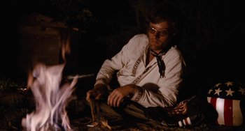 Movie still from “Easy Rider” (1969), directed by Dennis Hopper – A man sitting in front of a fire with a knife; Medium shot, Low angle