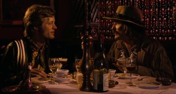 Movie still from “Easy Rider” (1969), directed by Dennis Hopper – Two men sitting at a table with wine glasses; Medium shot, Over the shoulder angle
