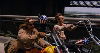 Movie still from “Easy Rider” (1969), directed by Dennis Hopper – A group of men riding motorcycles on a street; Wide shot, Low angle