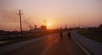 Movie still from “Easy Rider” (1969), directed by Dennis Hopper – Two people riding motorcycles down a street at sunset; Extreme Wide shot, Low angle