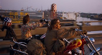 Movie still from “Easy Rider” (1969), directed by Dennis Hopper – A man and a woman riding on a motorcycle; Wide shot, Low angle