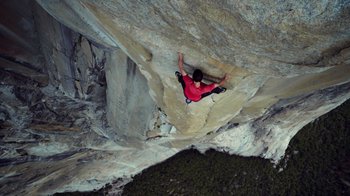 A man in a red shirt climbing a rock wall