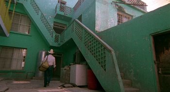 Movie still from “El Mariachi” (1992), directed by Robert Rodriguez – A man walking up a set of stairs in a building; Wide shot, Low angle